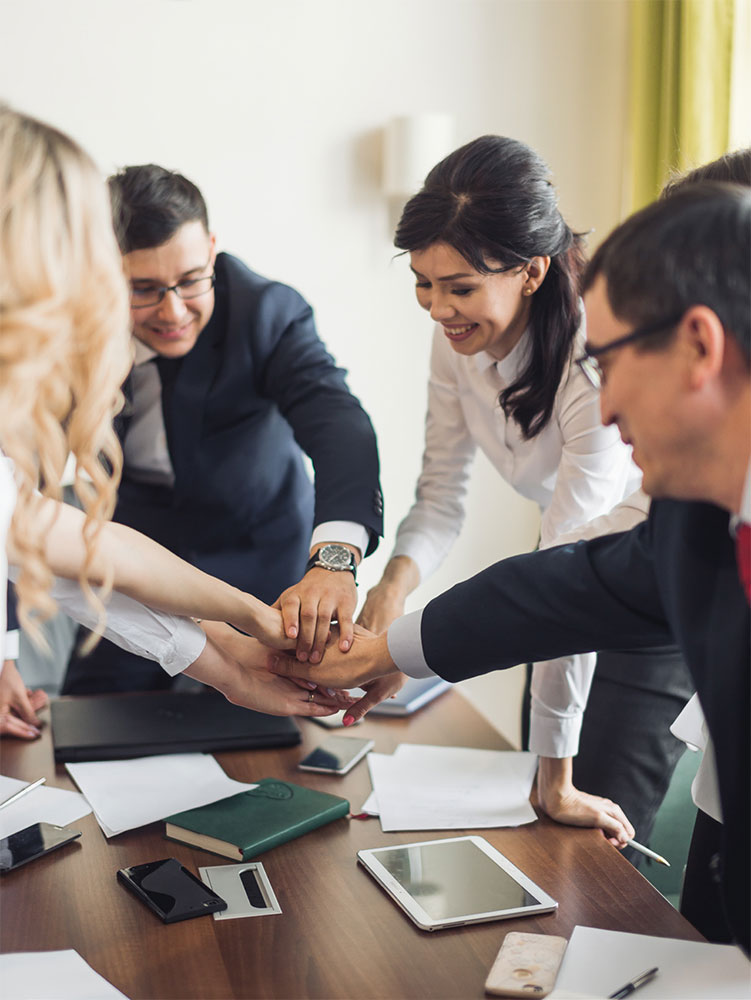 photo of business professionals putting their hands together as a team in a huddle